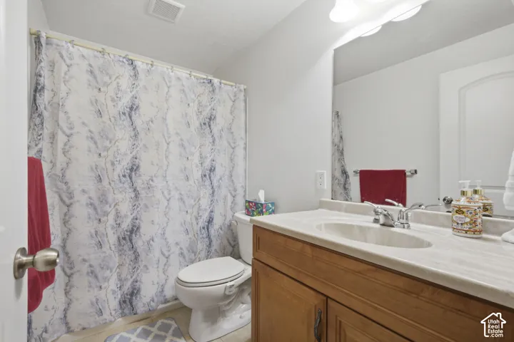 Bright bathroom featuring a wood-finish vanity with ample countertop storage, white countertop, and an integrated sink