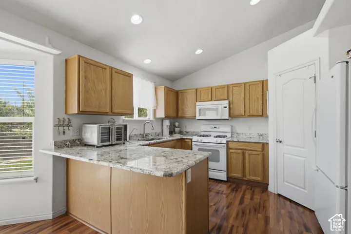 Kitchen featuring wood-finish cabinetry, granite countertops, white appliances, and bamboo flooring