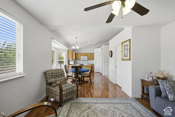 Open-concept living area featuring bamboo flooring, a ceiling fan with integrated lighting, and white walls