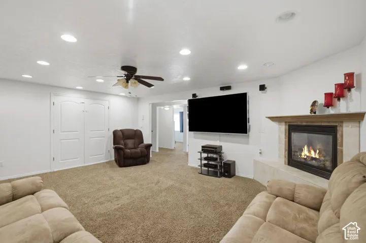 Spacious living area featuring a corner fireplace, a ceiling fan with integrated lighting, recessed ceiling lights, and carpet