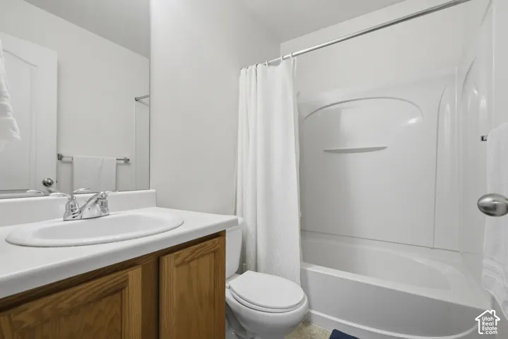 Clean and functional full bathroom featuring a wood-finish vanity with an integrated sink, white countertop, chrome faucet, and large mirror