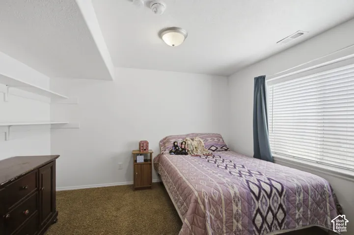 Spacious secondary bedroom featuring a large window, carpeted flooring, and built-in wall shelving