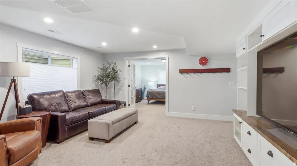 Carpeted recreation room featuring recessed lighting, a built-in entertainment center with white cabinetry, a wood-finish countertop, and a window with a privacy blind