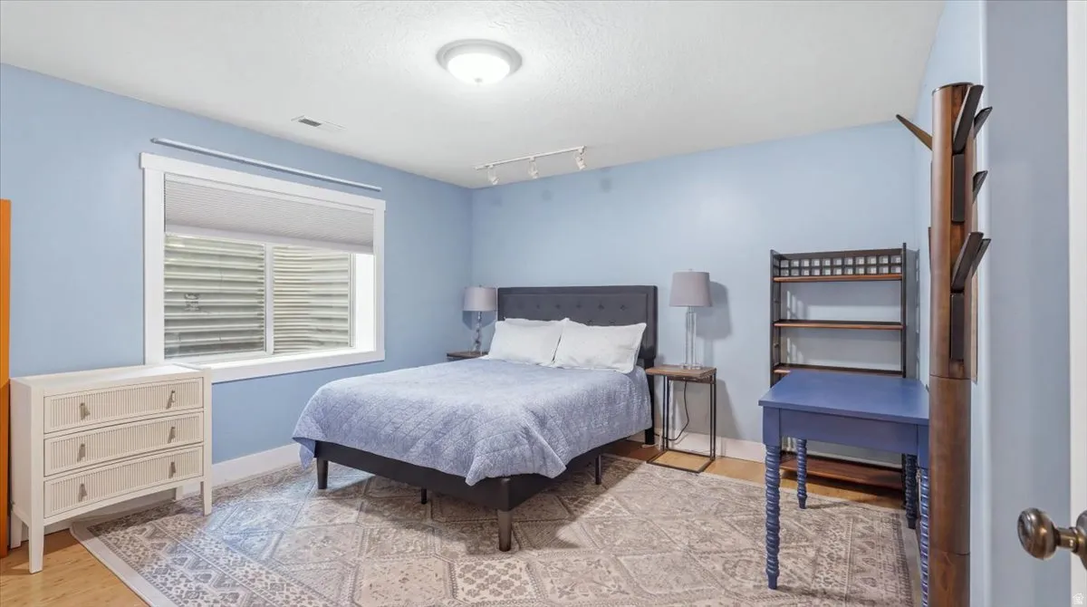 Light blue walls with white trim, wood-finish flooring, a flush-mount ceiling light, and a window with horizontal blinds