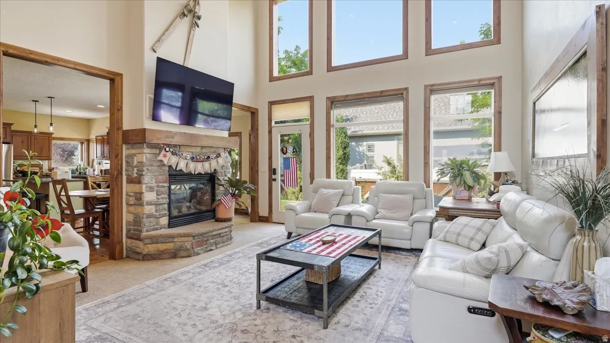 Soaring vaulted ceilings and abundant natural light define this expansive great room, anchored by a wood-burning fireplace with stone surround and hearth