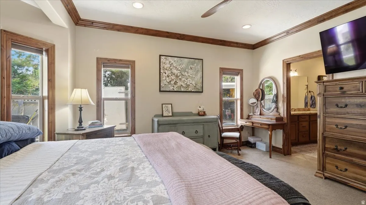 Spacious primary bedroom featuring hardwood flooring, coffered ceiling detail with wood trim, and abundant natural light from multiple windows