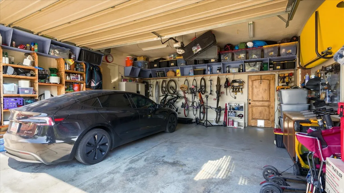 Spacious garage featuring a concrete floor, built-in shelving, and a natural wood-finish interior door