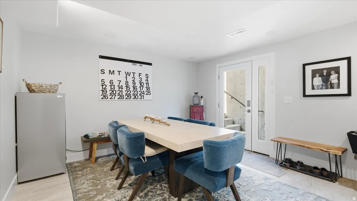 Spacious dining area featuring neutral wall tones, recessed lighting, and dual glass-paneled doors