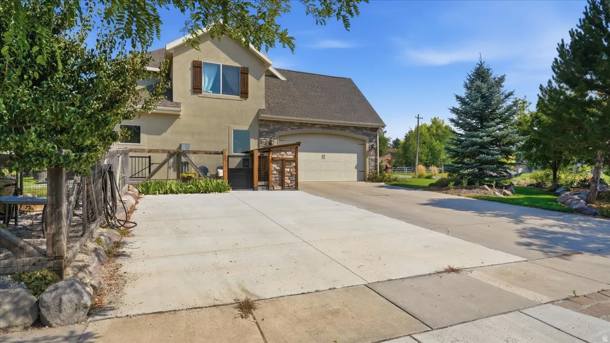 Two-story residence featuring a spacious concrete driveway with multiple parking sections, attached two-car garage with paneled doors, and a stucco exterior