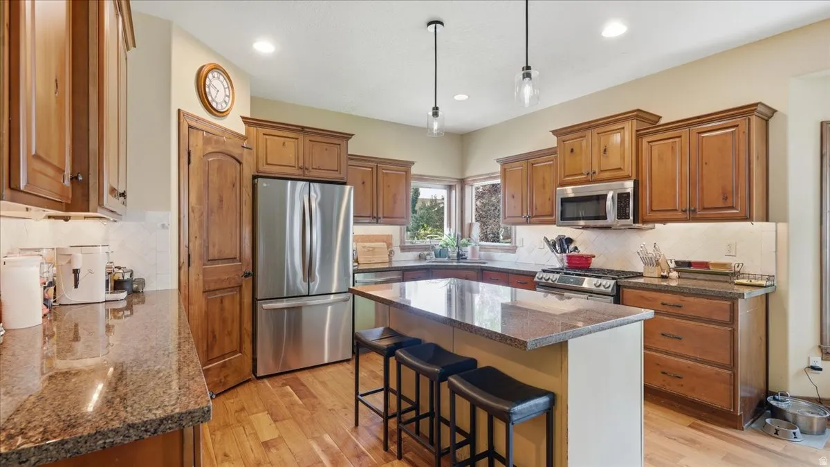 Gourmet kitchen featuring warm wood cabinetry, stainless steel appliances, granite countertops, and a spacious center island with seating