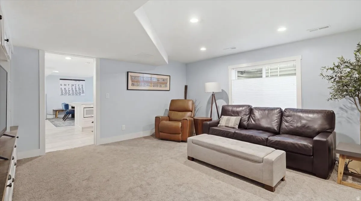 Spacious recreation room featuring neutral carpet flooring, recessed ceiling lighting, and large windows with plantation shutters