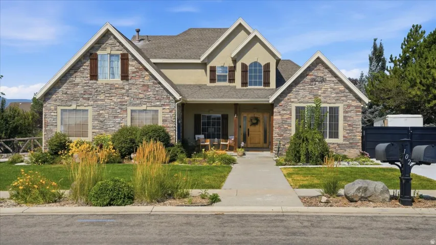 Stunning two-story brick and stone residence featuring a welcoming front elevation with arched entryway, multi-pane windows, and a peaked roofline with stone accents