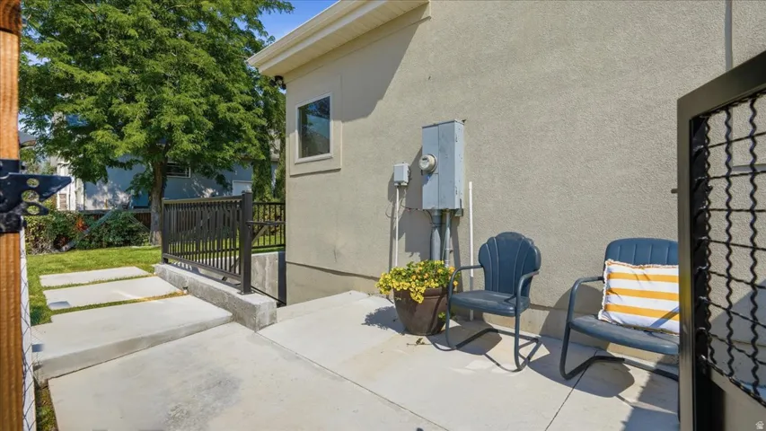 Expansive concrete patio with mature landscaping and shade trees, featuring comfortable outdoor seating areas and direct access to the residence
