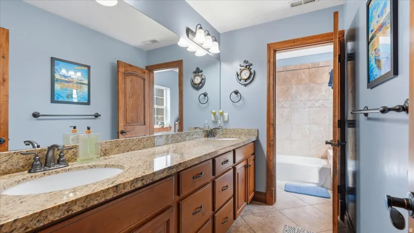 Spa-inspired master bath featuring dual vanities with granite countertops, wood cabinetry, and brushed nickel fixtures