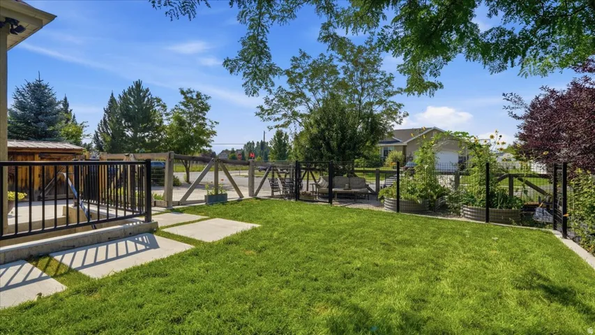Expansive backyard oasis featuring a manicured lawn, mature landscaping with mixed tree varieties, and a composite deck with black metal railing system