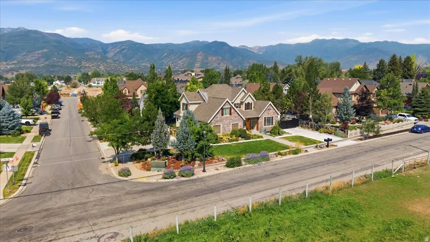Striking two-story residence featuring a brick and stone exterior, situated on a spacious corner lot with mature landscaping, manicured lawn, and established trees