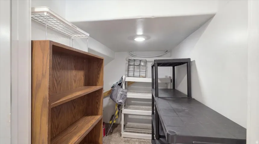 Utility room featuring sturdy wood-finish cabinetry with open shelving, industrial-grade metal shelving units with wire racks, concrete flooring, and recessed ceiling lighting