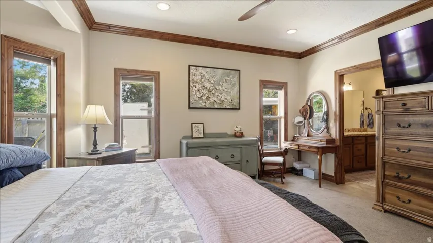 Spacious primary bedroom featuring hardwood flooring, coffered ceiling detail with wood trim, and abundant natural light from multiple windows