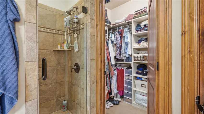 Primary Bathroom and Walk-In Closet Suite featuring a frameless glass-enclosed shower with tile surround, brushed nickel fixtures, and dual-entry design
