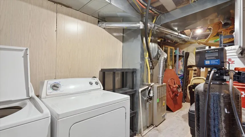 Utility room featuring side-by-side washer and dryer, built-in cabinetry, and ample storage space with wall-mounted organization systems and overhead shelving