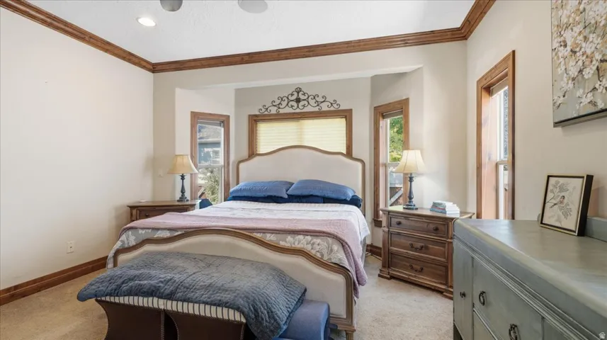 Serene primary bedroom featuring a decorative metal headboard, blue upholstered bedding, wood-trimmed ceiling detail, and dual glass-paned doors with wood frames flanking the bed