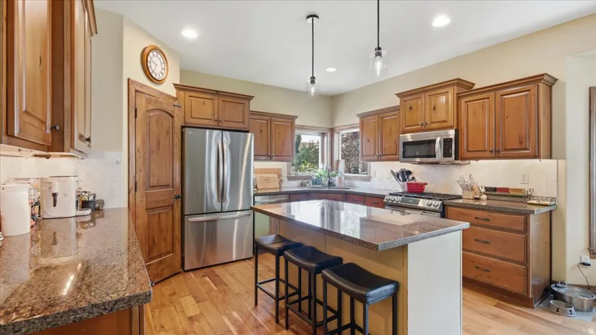 Gourmet kitchen featuring warm wood cabinetry, stainless steel appliances, granite countertops, and a spacious center island with seating