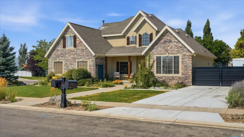 Striking two-story home featuring a mixed stone and stucco exterior with peaked gables and arched entryway