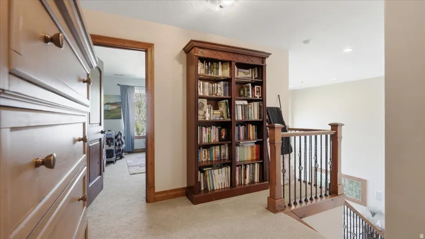 Upstairs landing featuring built-in wood cabinetry with extensive shelving and storage, hardwood-finish flooring, and a wooden stair railing with spindle balusters