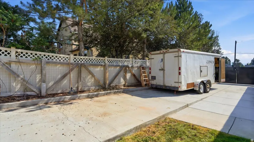 Expansive concrete driveway with dual-axle enclosed trailer featuring wood-trimmed entry doors and professional-grade construction
