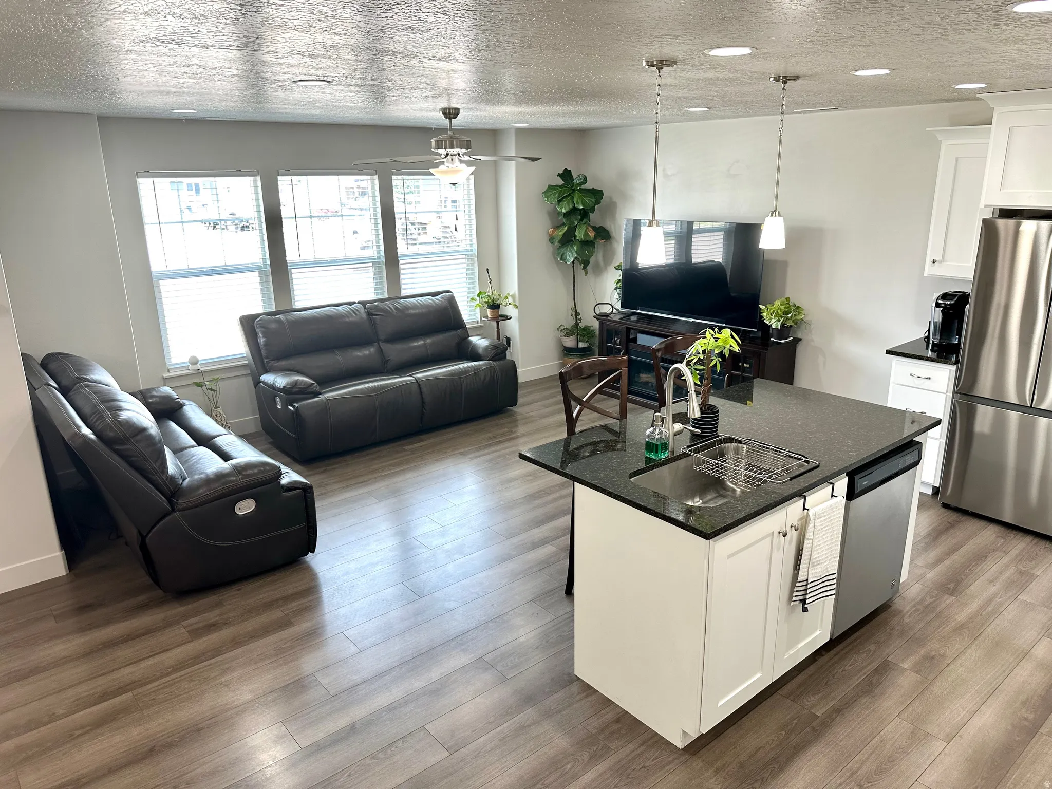 Open-concept living space featuring wood-finish flooring, recessed lighting, and a ceiling fan
