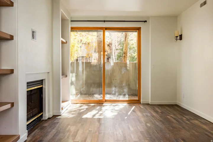 Spacious room featuring wood-finish flooring, a built-in fireplace, and integrated shelving