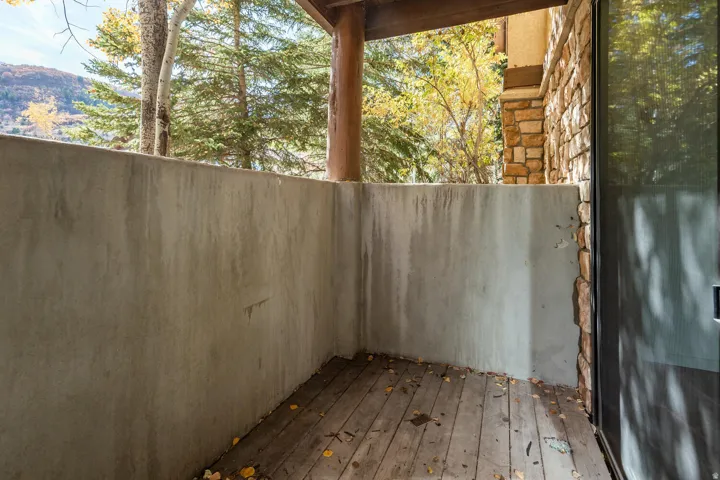 Covered deck featuring composite decking, concrete privacy walls, and timber support beams