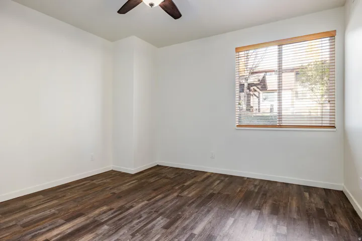 Room with wood-finish flooring, a window featuring horizontal blinds, and a ceiling fan with integrated lighting