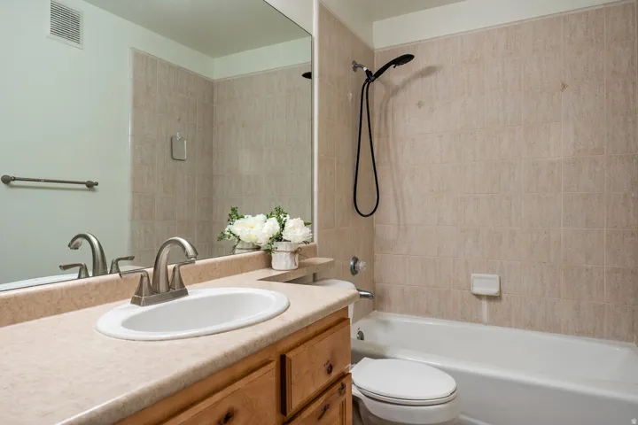 Spa-inspired primary bathroom featuring a wood-finish vanity with dual sinks, marble-look countertop, and brushed nickel fixtures