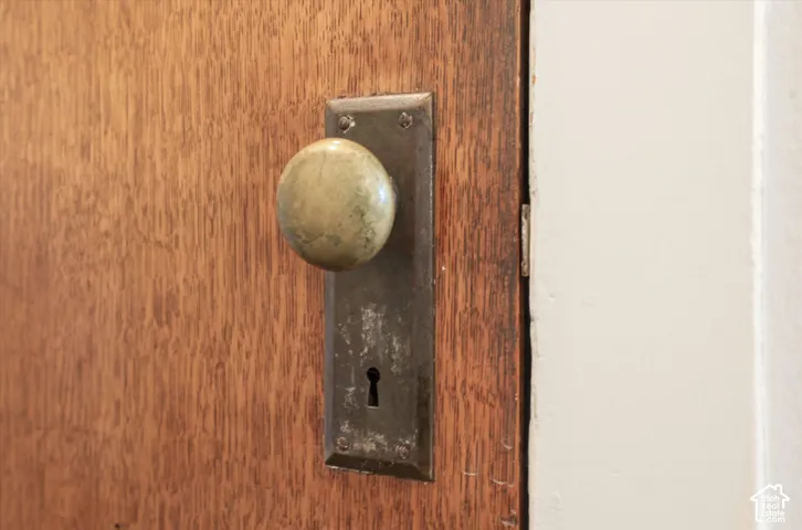 Vintage brass door knob and dark metal escutcheon plate with keyhole detail mounted on warm wood-finish door