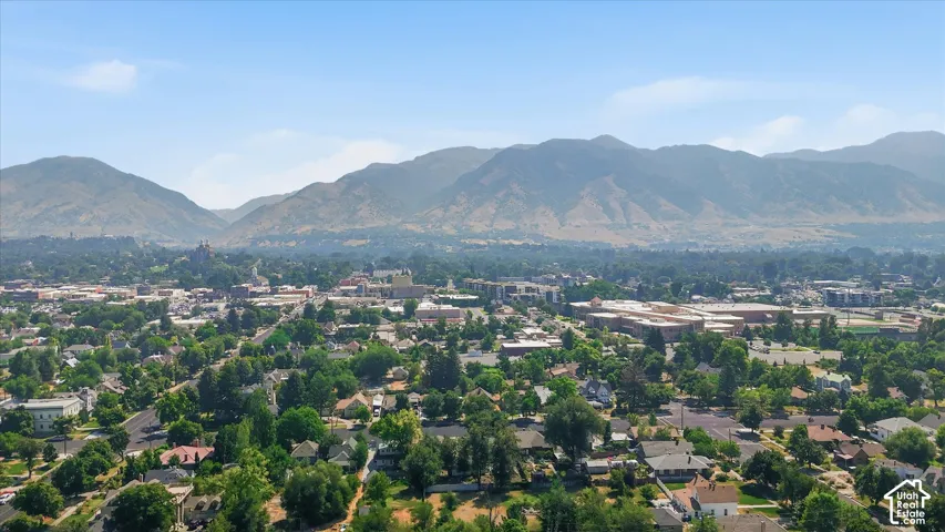 Expansive urban landscape featuring a variety of architectural styles, mature trees, and mountainous terrain in the background