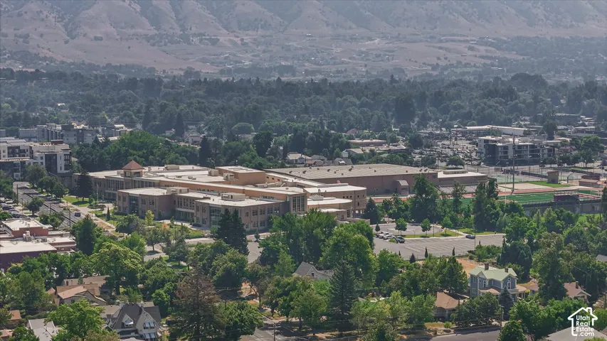 Aerial perspective showcasing a substantial institutional or commercial structure with expansive copper-toned roofing, surrounded by mature landscaping and tree coverage