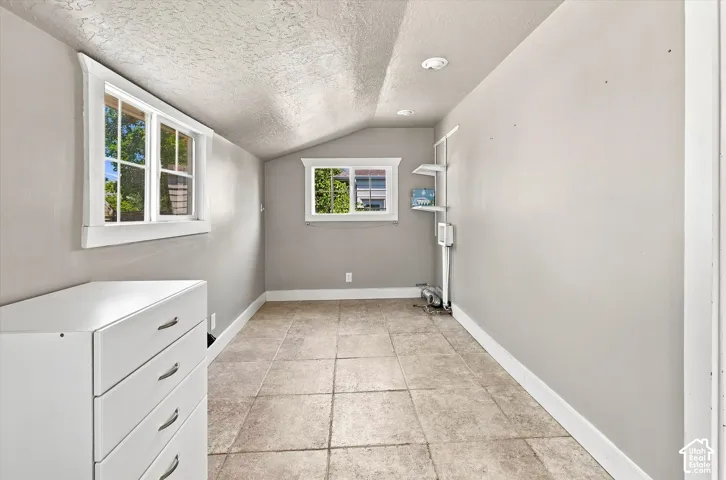 Spacious utility room featuring tile flooring, white cabinetry with multiple drawers, large windows with natural light, recessed ceiling lighting, and neutral wall finishes throughout