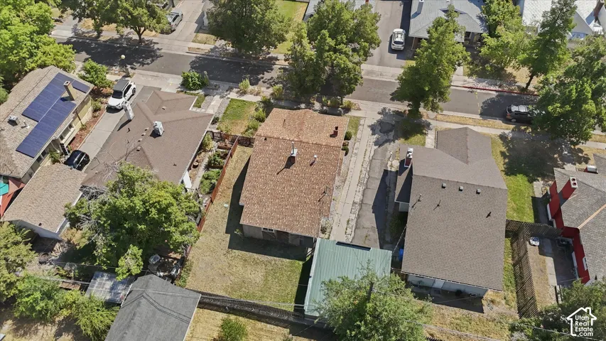 Aerial view showcasing this multi-structure property featuring multiple rooflines with varied materials including tile and composition shingles, mature landscaping with established trees throughout the lot, and ample paved surfaces