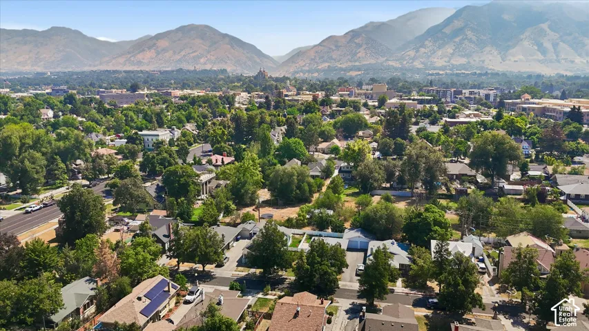 Aerial view showcasing this tree-lined residential neighborhood with mature landscaping, distant mountain backdrop, and established single-family homes throughout the community