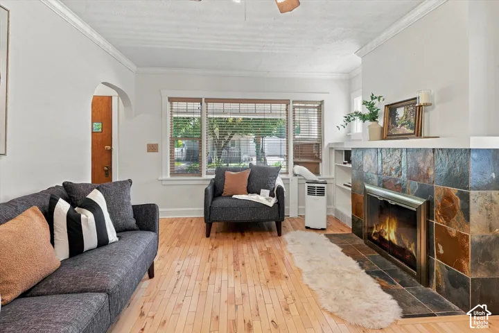 Bright, light-filled living room featuring hardwood flooring, a fireplace with decorative tile surround and built-in media console, and expansive windows with plantation shutters