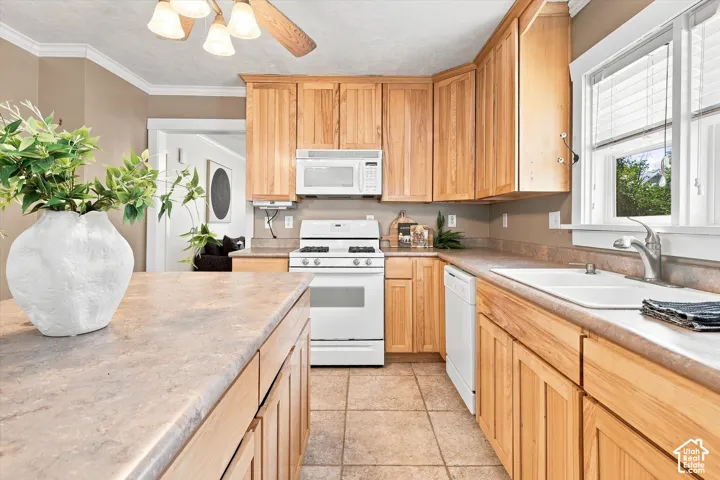 Kitchen featuring light wood cabinetry, white appliances, dual basin sink, ceiling fan with light fixture, and tile flooring