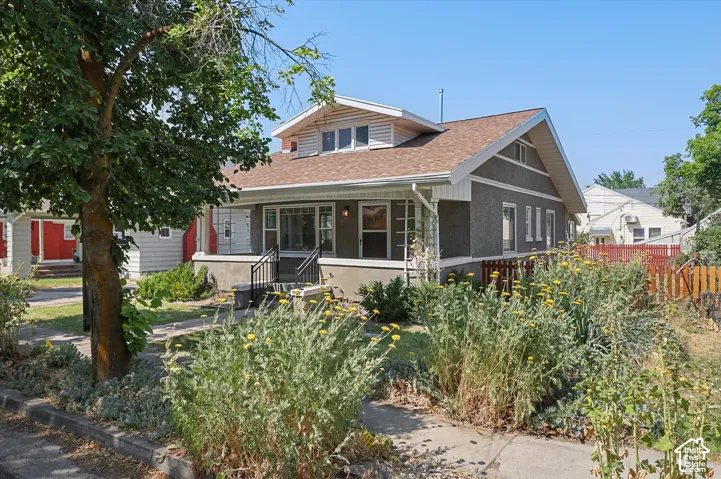 Charming Craftsman-style home featuring a dark exterior finish with gabled roofline and dormer window