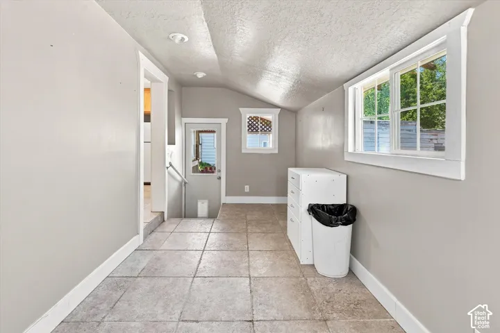 Tiled flooring extending through a versatile area with a pitched ceiling