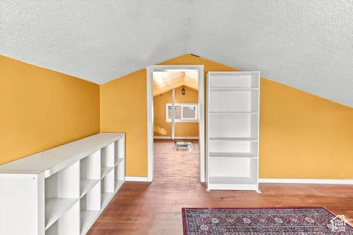 Charming attic bedroom featuring angled ceilings, white built-in shelving units, and warm golden-yellow walls