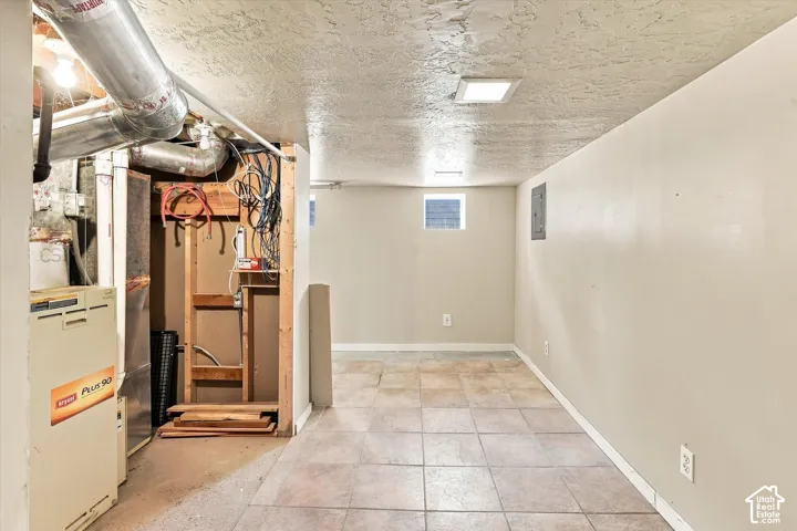 Spacious utility room featuring tile flooring, recessed ceiling lighting, and mechanical systems including a furnace and water heater
