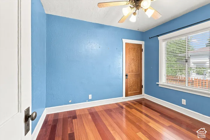 Bright bedroom showcasing rich wood-finish flooring, crisp white trim, and soft blue wall paint