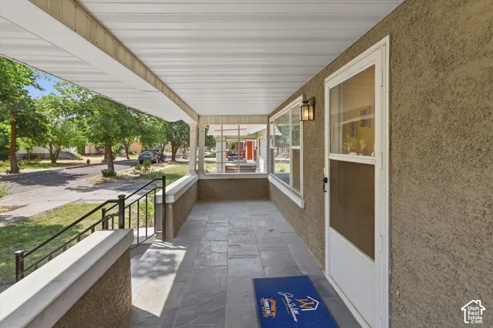 Covered front porch featuring a corrugated metal ceiling, slate-finish tile flooring, and black metal railings
