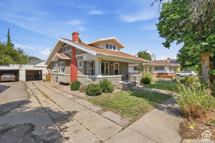 Craftsman-style home featuring a covered front porch, a dormer window, and a prominent red brick chimney