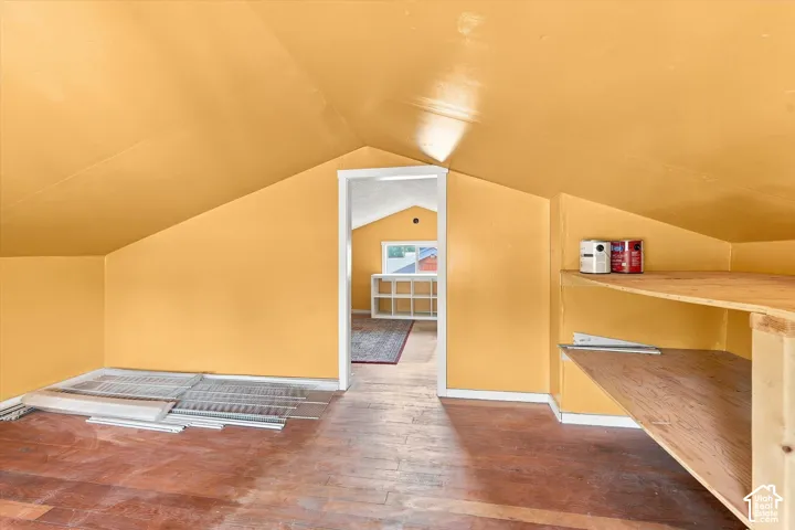 Spacious attic room featuring sloped ceilings, wood-finish flooring, and abundant natural light from overhead skylights
